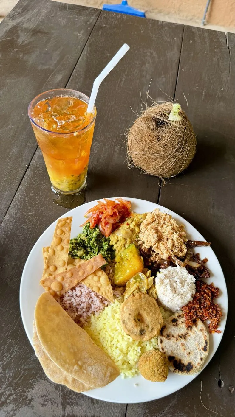 My buffet plate: red and yellow rice, dhal, pumpkin, pol sambol, gotu kola, papadam, roti and vadai, with a passion-fruit iced tea