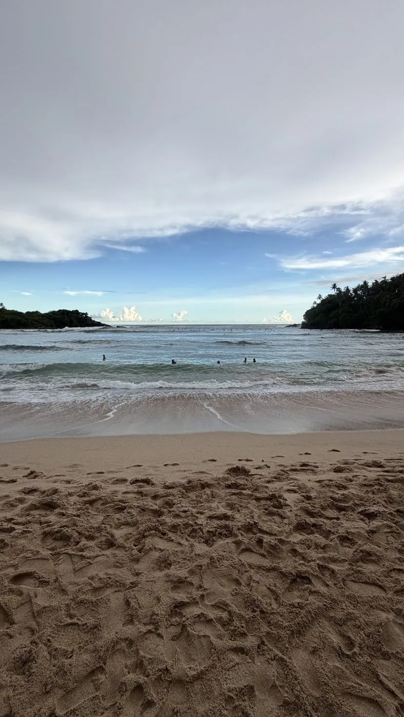 Hiriketiya's horseshoe bay, swimmers and surfers out past the break