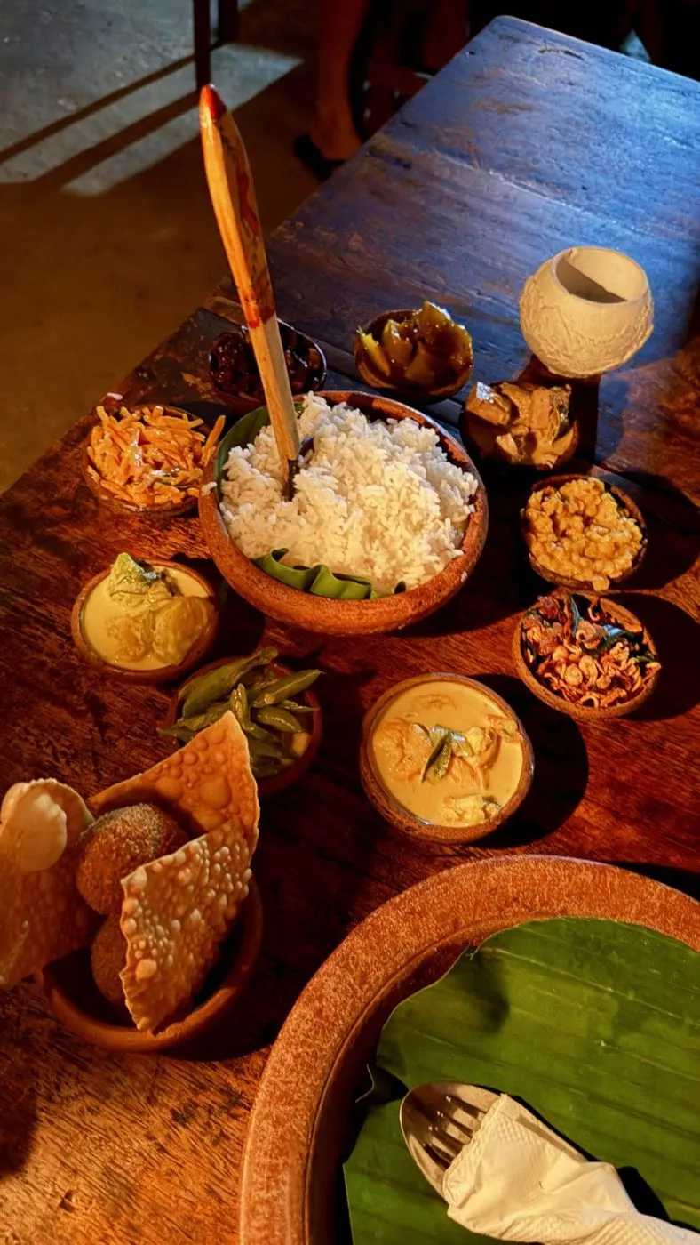 The full spread: rice surrounded by coconut-shell bowls of curries and sambols