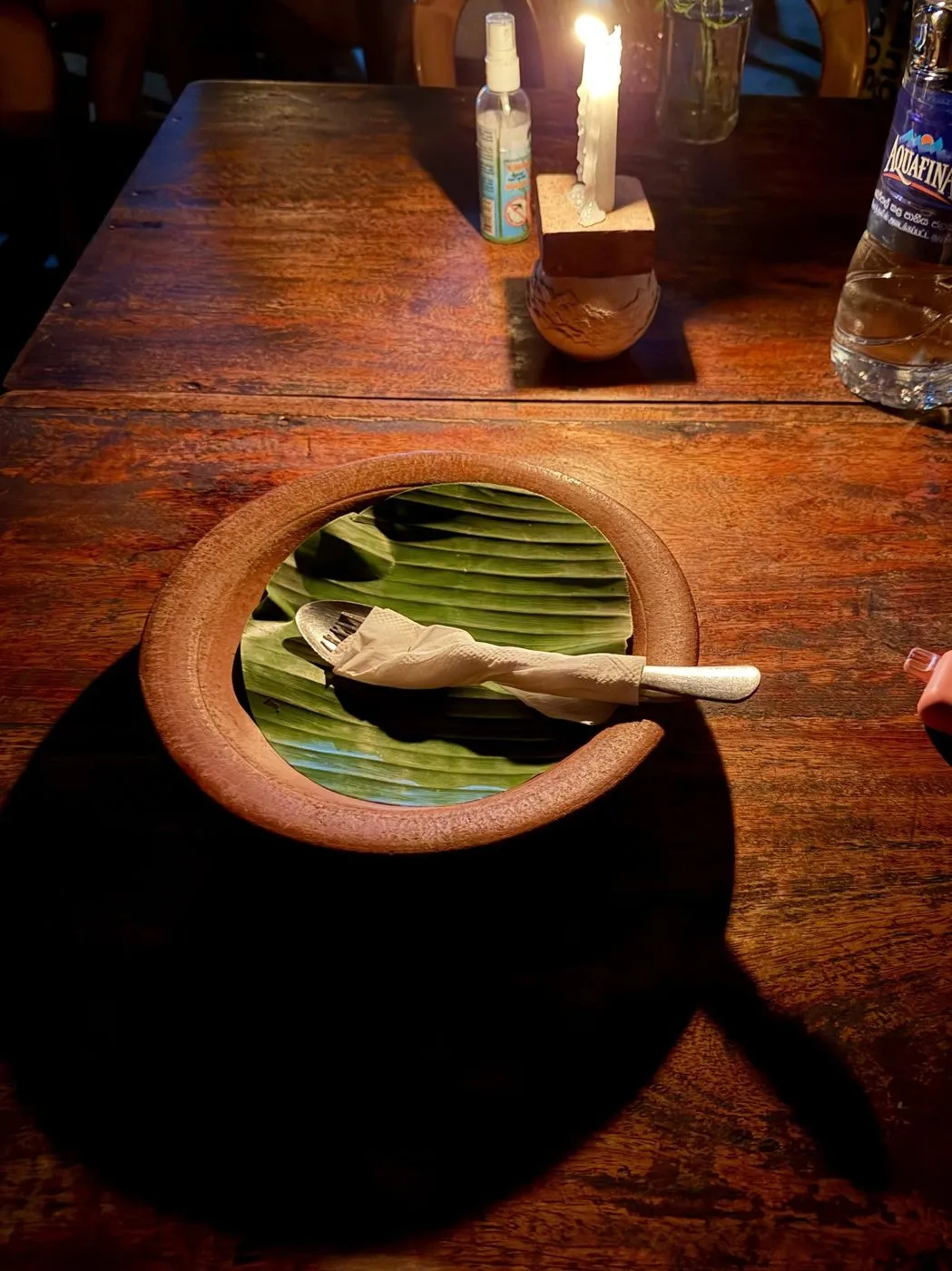 Clay plate lined with a banana leaf, waiting by candlelight
