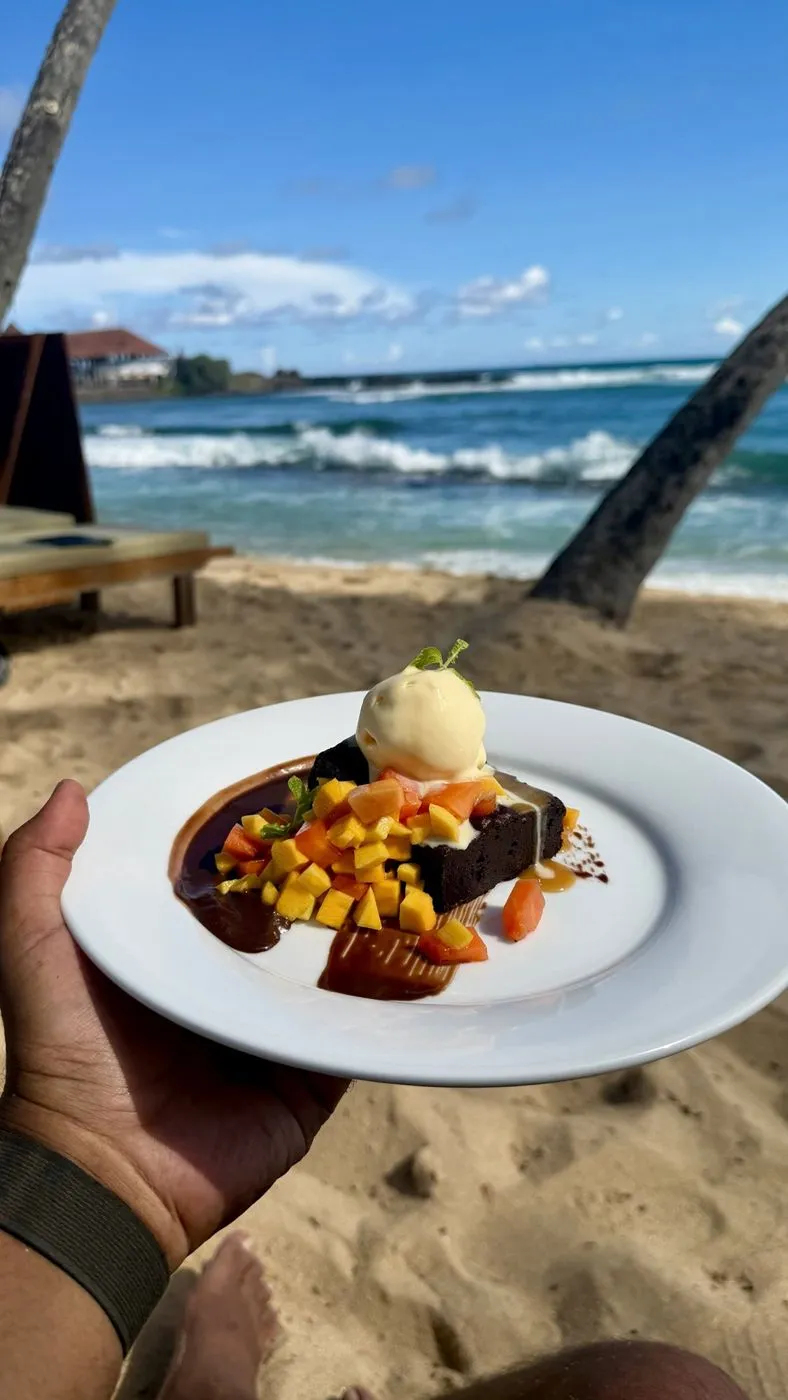 Brownie with ice cream, mango and papaya, eaten barefoot on the sand