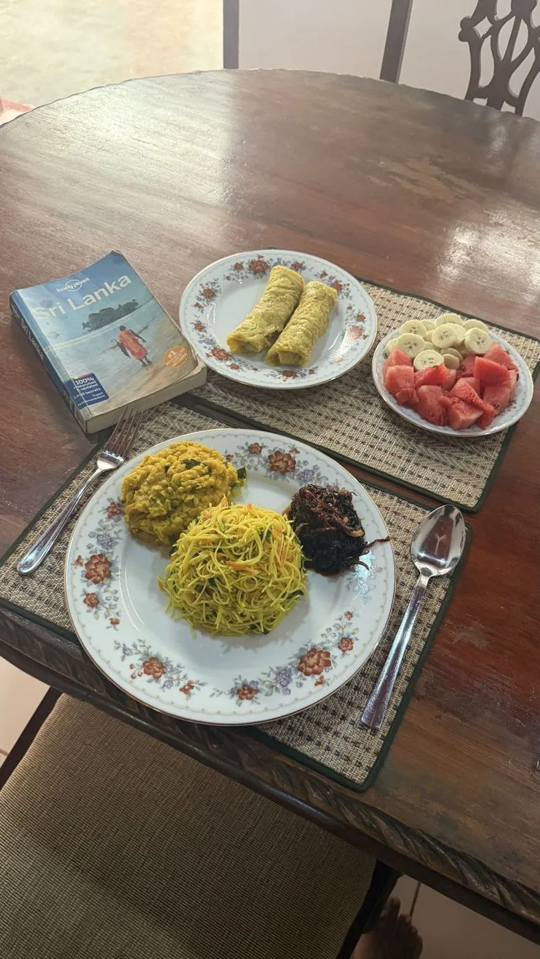 Sri Lankan breakfast at Old Parkland: string-hopper pilau, dhal, seeni sambol, egg rolls and fruit, with the Lonely Planet