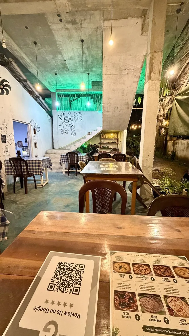 Open dining space with gingham tablecloths and a 'Vegan meal' mural