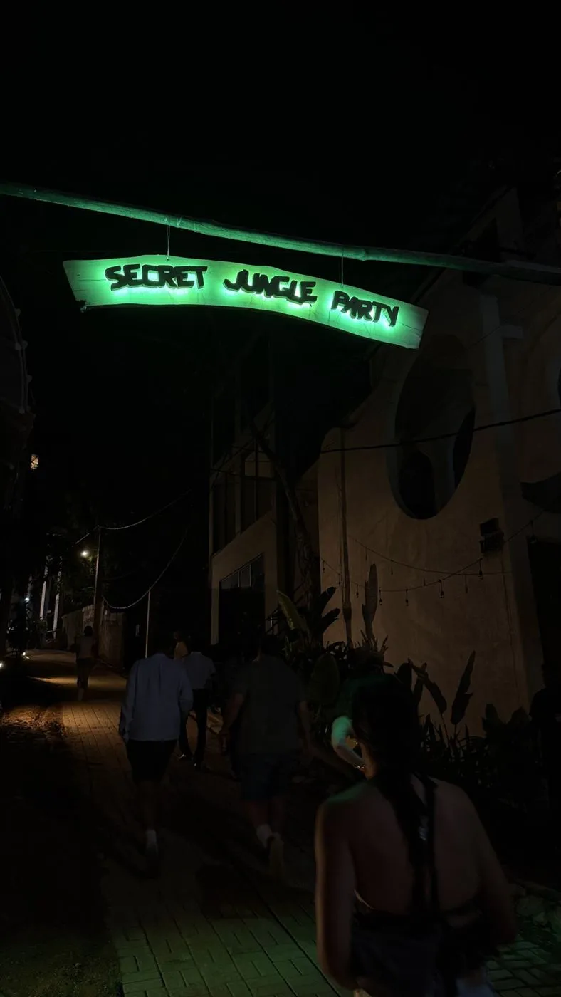 Walking in under the glowing green Secret Jungle Party sign
